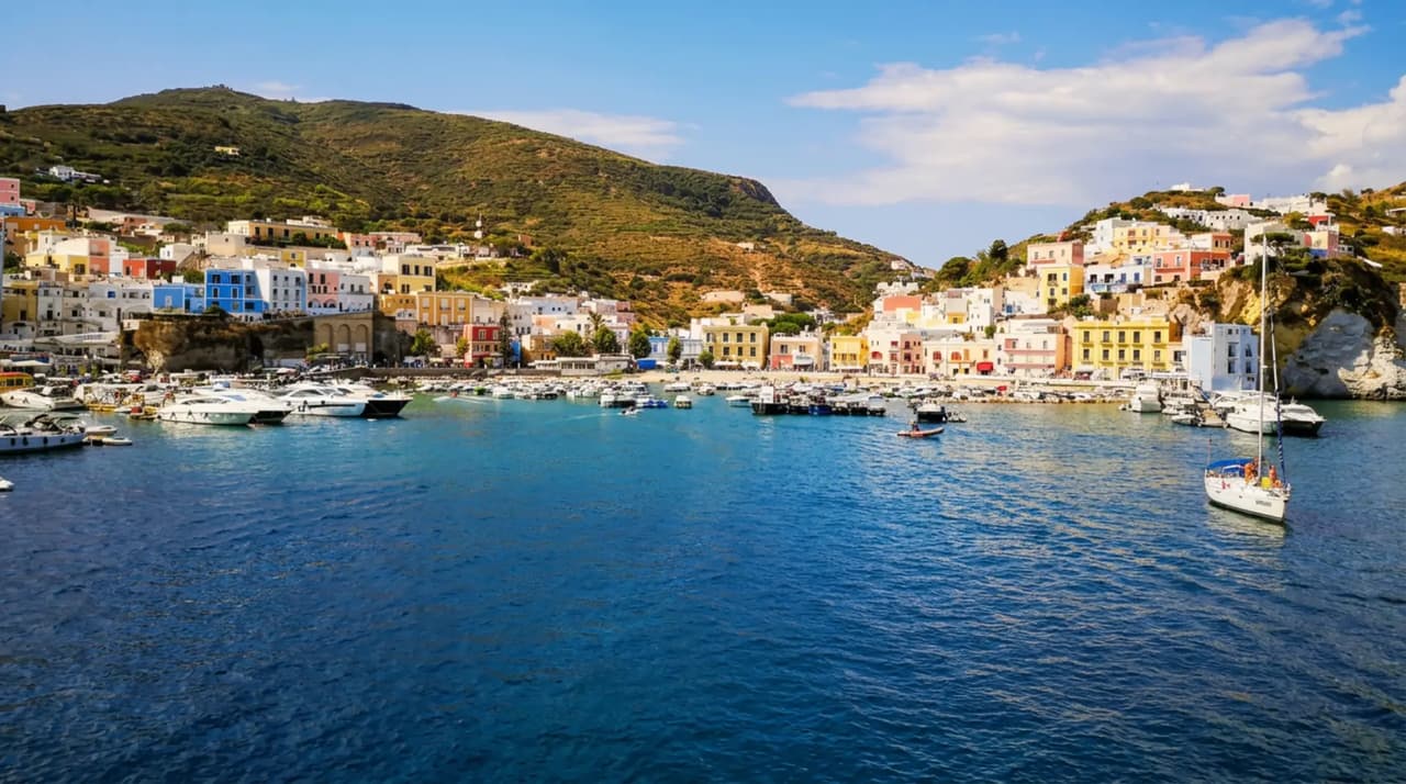 Il porto di Ponza visto dal mare, con le case colorate sul lungomare e le barche ormeggiate
